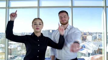 Happy young colleagues advertise their company. Cheerful girl and handsome guy invite to join to their work gesticulating a lot in office center. video