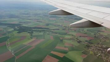 szenisch Antenne Aussicht von ein Flugzeug Fenster präsentieren bunt Patchwork Ackerland, Wind Turbinen, und verstreut Dörfer video