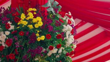 A close-up view of a decorative railing draped with red and white fabric, creating a festive atmosphere. The background features greenery and a blurred building, suggesting an outdoor event. video