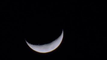 A close-up view of a crescent moon against a dark night sky, showcasing its illuminated video