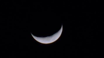 A close-up view of a crescent moon against a dark night sky, showcasing its illuminated surface video