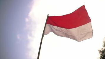 A close-up view of the Indonesian flag waving against a bright sky. The flag features horizontal stripes of red and white, symbolizing courage and purity. video