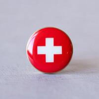 A red and white swiss flag pin on a white background photo