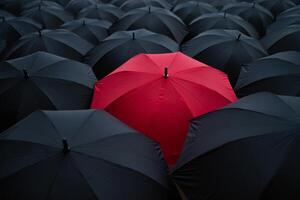 A red umbrella in a crowd of black umbrellas photo