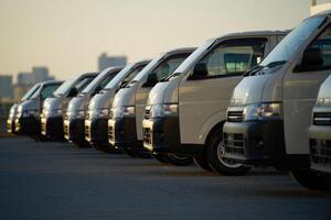 A row of white vans parked in a parking lot photo