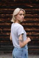 A woman with tattoos standing in front of a wooden wall photo