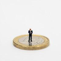 Miniature man standing on top of a euro coin photo
