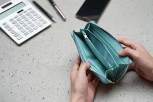 A person holding an empty wallet next to a calculator photo
