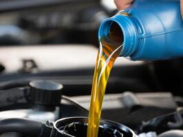 A person pouring oil into a car engine photo