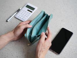 A person holding a wallet with a cell phone and calculator photo