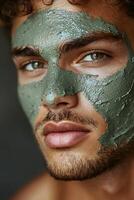 Close-up of a man applying green clay mask on his face photo