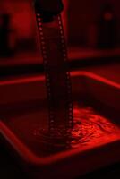 Moody analog film strip developing under red darkroom light photo