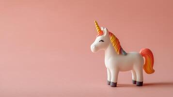 A toy unicorn is standing on a pink background photo