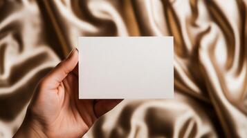 A hand holding a blank card on a gold background photo