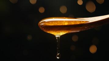 Honey dripping from a wooden spoon on a black background photo