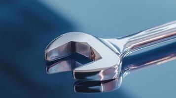 A close-up view of a shiny wrench laying on a reflective surface. photo