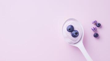 Yogurt with blueberries on a spoon on a pink background photo