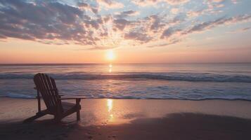 A chair sits on the beach at sunset photo