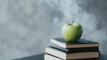 An apple sits on top of a stack of books photo