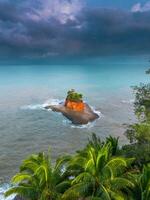 A small island surrounded by palm trees on a cloudy day photo