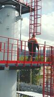Aerial view gas station operator climbs to the top of the station. Modern gas complex in the mountains. A gas worker climbs the ladder of the gas distribution unit against the backdrop of mountainous video