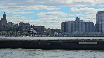 Helicopter hovering over water at Manhattan heliport, city skyline in background under cloudy sky video