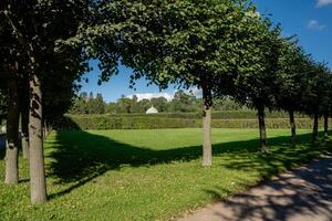 Visiting Catherine Palace with its beautifully manicured gardens and an inviting green lawn under a clear blue sky during the summer photo