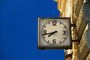 Clock on a building against a clear blue sky in St. Petersburg, marking the late afternoon with shadows stretching on the wall photo