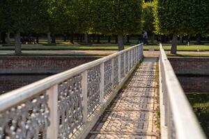 Strolling along the elegant bridge at Peterhof gardens during a sunny day brings tranquility and scenic beauty photo