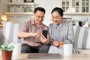 Couple enjoy using mobile phone on sofa. grandparent learning and connecting with social media, vdo call with family, shopping online, surfing the internet. photo