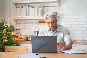 Senior man learning or working with laptop in the morning at home photo