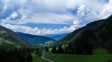Breathtaking valley view under a dynamic sky filled with clouds in the heart of the mountains during a sunny summer afternoon photo