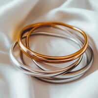 Elegant metal bangles resting on soft fabric photo