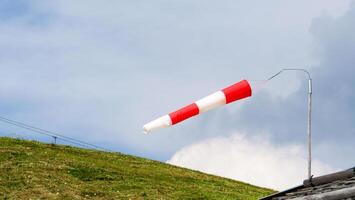 Colorful wind sock dances in the breeze against a backdrop of lush hills and clouds on a clear afternoon photo