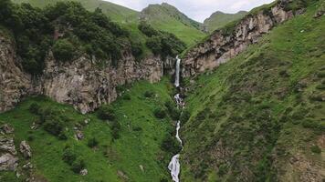 Aerial zoom hidden waterfall cascades down a remote cliff side in the Caucasus Mountains of Georgia.Wilderness, tranquil scene the raw beauty. Mist rises gently as water flows into a forested ravine video