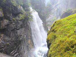 Majestic waterfall cascading through rocky cliffs in a misty forest setting during midday photo