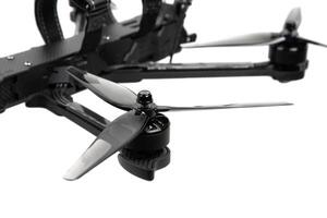 Close-up of FPV drone propeller and motor assembly on carbon fiber arm with blurred back photo