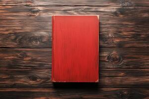 Closed red book with textured cover and aged edges lying on wooden surface photo
