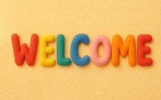 WELCOME word on yellow background composed from colorful felt letters photo