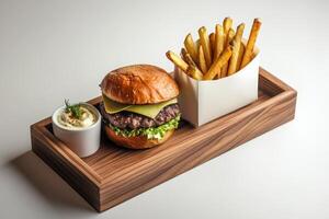A wooden tray with burger, the fries in a paper box and a ceramic dipping cup of smoked sauce. photo