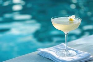 A glass filled with a sparkling citrus gin fizz rests on the edge of an infinity pool, where the water meets the horizon. photo