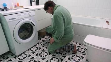 hombre haciendo lavandería en el baño cargando lavadora y jugando con gato en el baño video