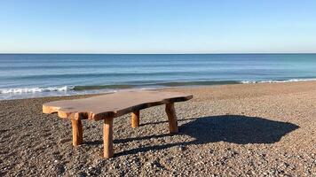 Rustic Wooden Table on Pebble Beach Shore and sea photo