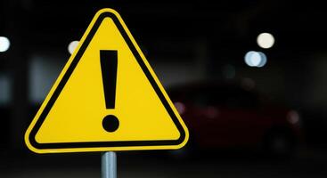 Yellow Caution Warning Sign with Exclamation Mark in Dark Parking Area photo