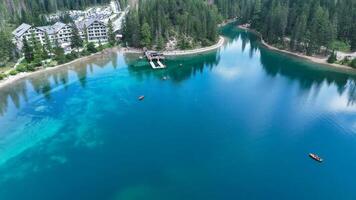 Captivating waters of a serene lake surrounded by towering trees and elegant lodges under a clear blue sky photo