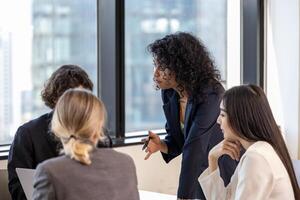 African woman sale manager is showing the annual report chart to her colleagues in the executive meeting for next year plan with market share increase for global business and investment concept photo