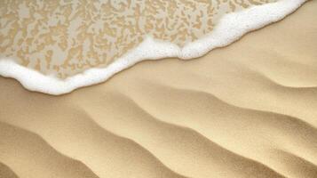Close-up of sandy beach with wave foam touching rippled sand patterns created by water photo