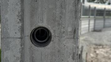 Concrete Wall with Circular Opening An industrial image shows a close-up of a gray concrete wall, a circular opening in its surface, highlighting texture, detail, and construction elements. photo