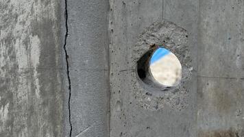 Concrete Hole A close up view of a circular hole drilled into a rough concrete surface, offering a glimpse of a blurred background beyond. photo