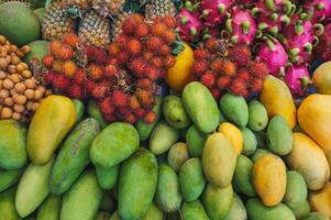 assortment of various tropical exotic Asian fruits on counter in a store in Vietnam. Vietnamese yellow and green mangoes, dragon fruit and rambutan photo
